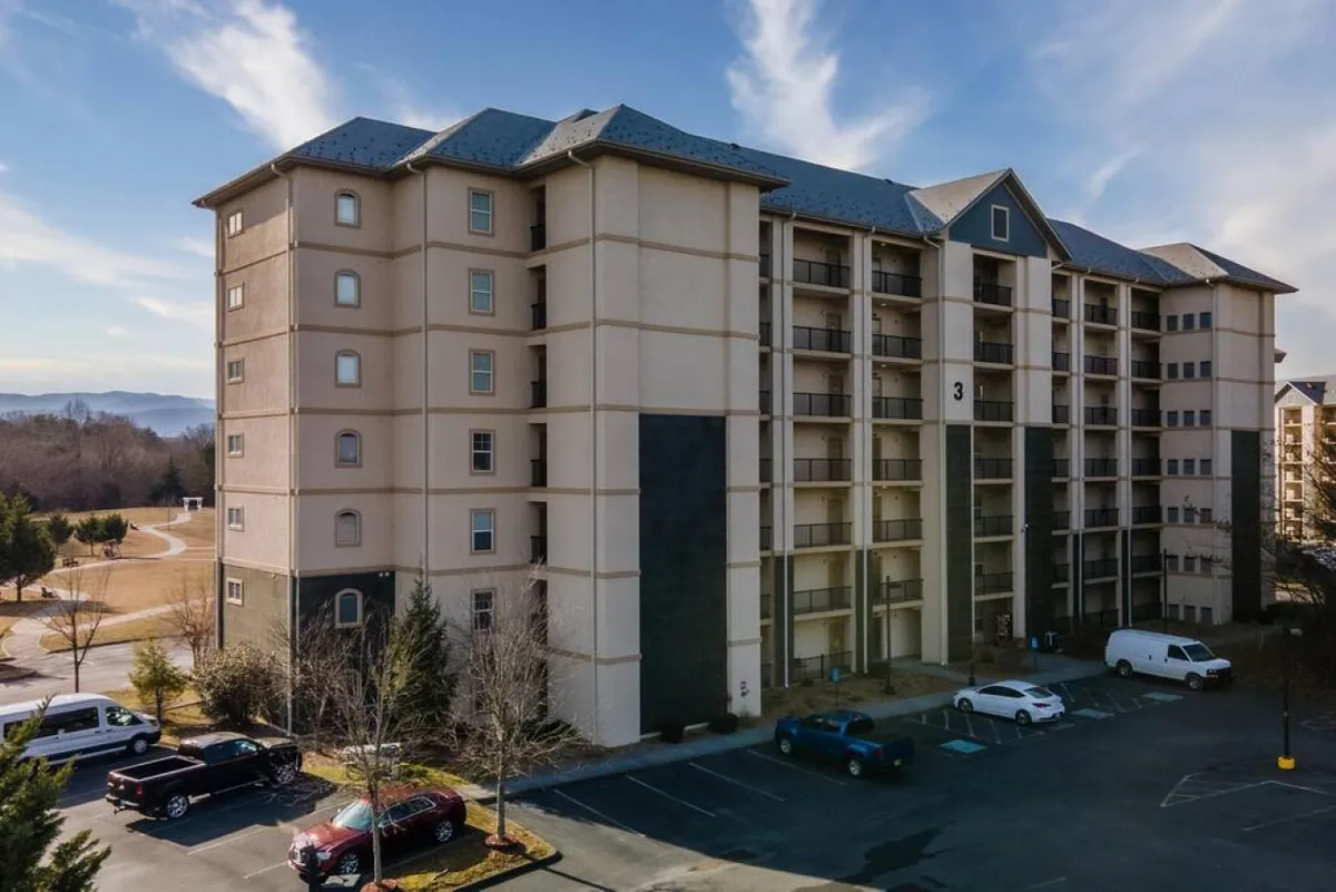 This exterior image shows the building facade of the property, surrounded by landscape and featuring visible parking. The setting is inviting, with a sense of convenience and accessibility, and hints at the communal, relaxed atmosphere guests can expect. The composition includes the parking lot, which ties directly to the mention of free parking in the section content.